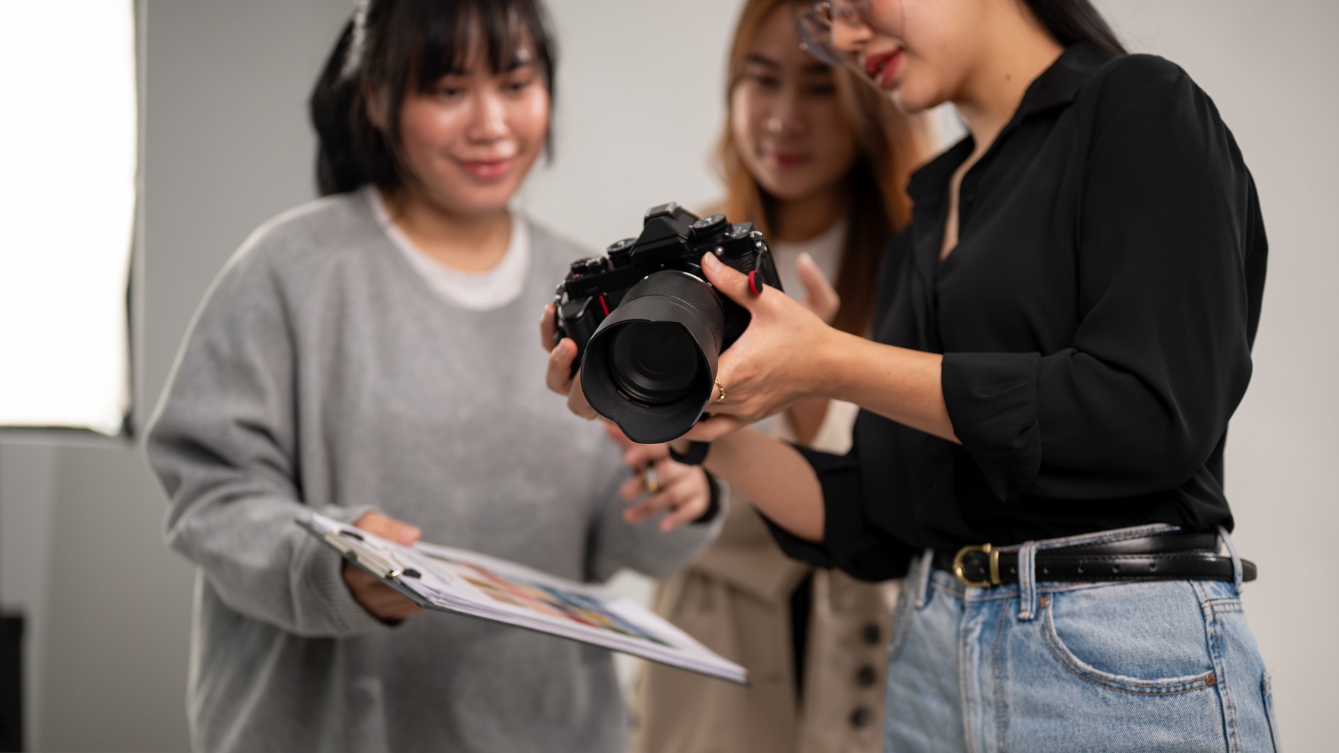 A photographer is showing images on her camera to art directors, working with her team in the studio